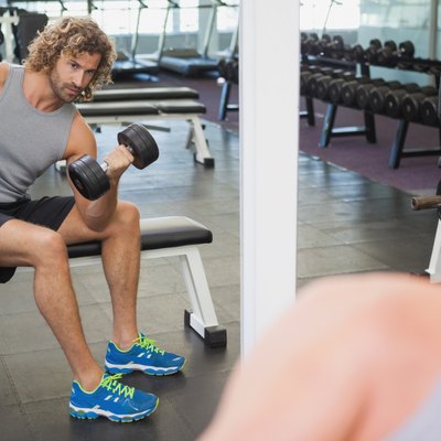 Young man exercising with dumbbell in gym