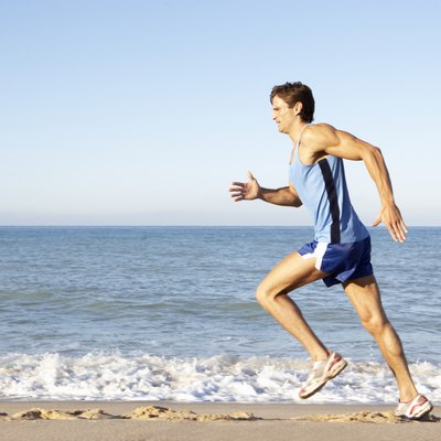 Young Man In Fitness Clothing Running Along Beach