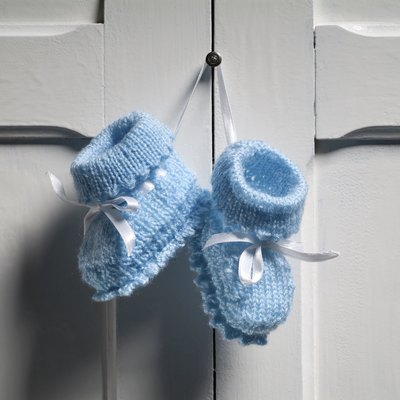Blue Baby Booties hanging on white door
