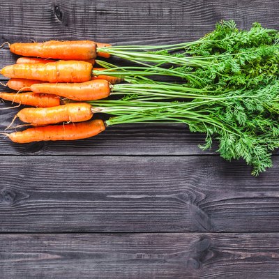 Ripe fresh carrots on a wooden background.