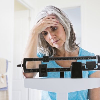 Unhappy Caucasian woman standing on weight scale