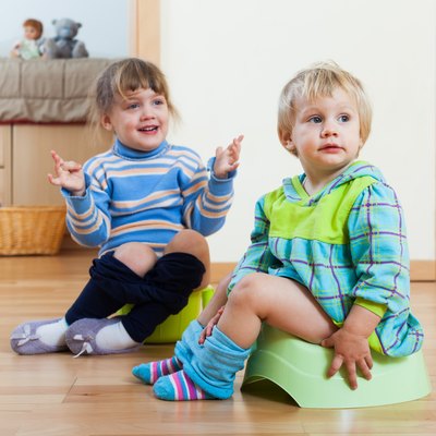 Two siblings sitting on chamber pots