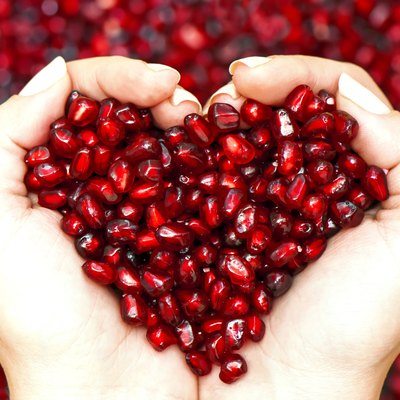 Pomegranate seeds shaping heart in hands