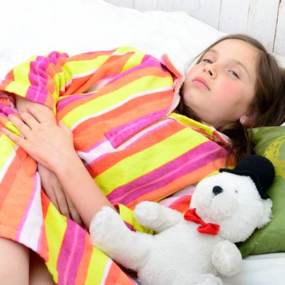 little girl in her bed has a stomachache
