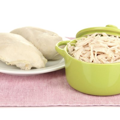 Shredded boiled chicken in green pan isolated on white