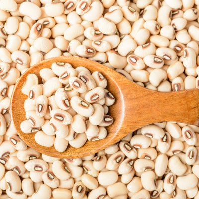 uncooked white cow pea beans in wooden spoon, top view