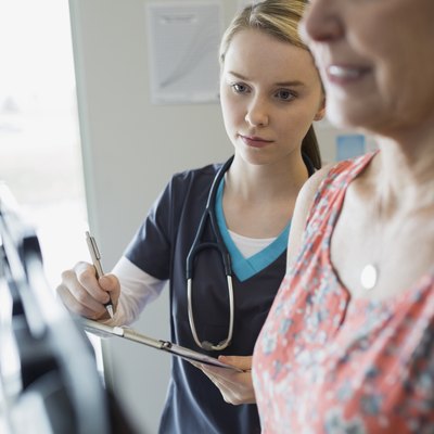 Nurse noting patients weight on scale in clinic
