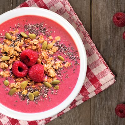 Raspberry smoothie bowl with superfoods on wood