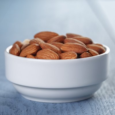 roasted almonds in white bowl on wooden table