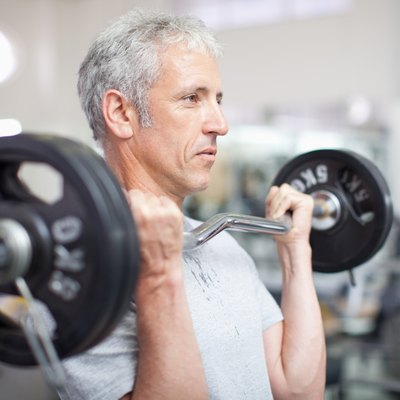 Portrait of smiling man holding barbell in gymnasium