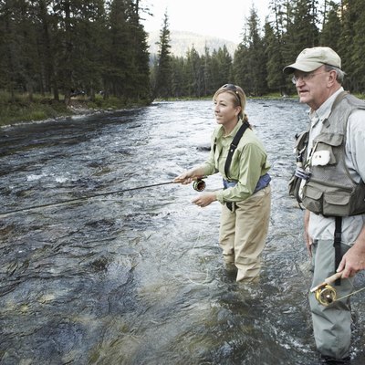 Senior man teaching woman fly-fishing