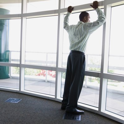 Rear view of a businessman leaning against a window frame