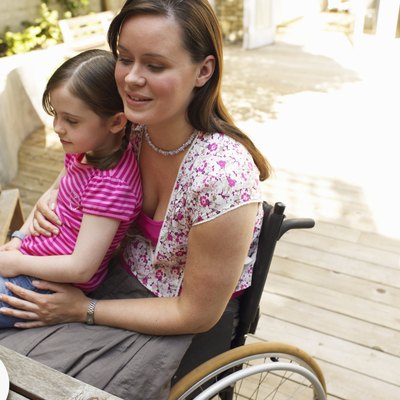 Woman sitting in wheelchair, with daughter (6-8) on lap, smiling