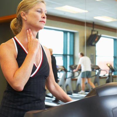 Woman checking her pulse on treadmill at gym
