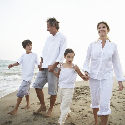 Family walking on beach, son and daughter (7-9) holding parents' hands