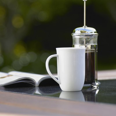 Coffee cup and plunger on table
