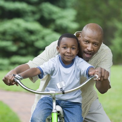 Portrait of a mid adult man teaching his son to how to ride a bicycle