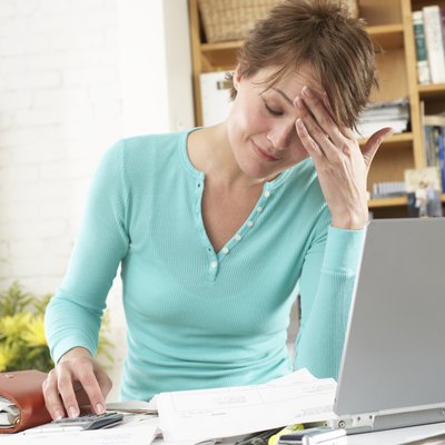 Woman by laptop in home office, hand on forehead