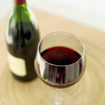 close-up of a glass of red wine with a wine bottle on a table