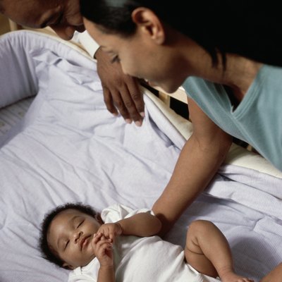 High angle view of parents looking at their baby boy sleeping in a crib