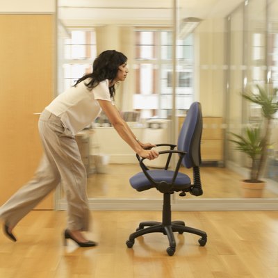 Hispanic businesswoman pushing office chair