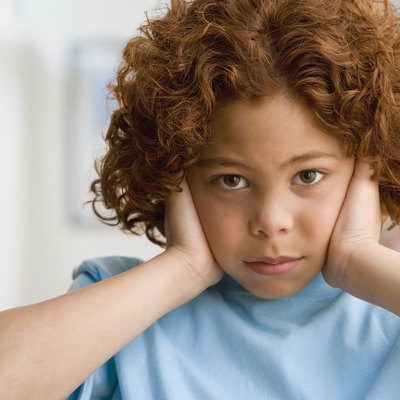 Mixed Race boy covering ears
