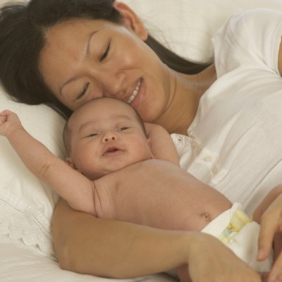 Asian mother laying in bed with newborn baby