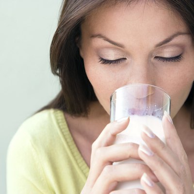 Young woman drinking milk, smiling, close-up