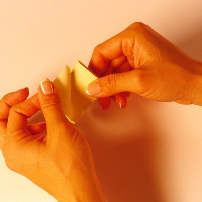 Woman's hands peeling off a post-it note.