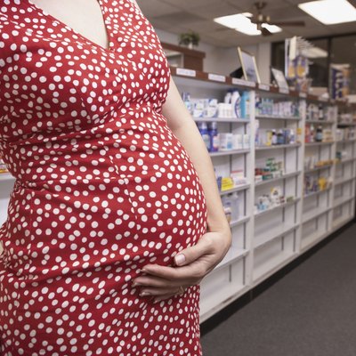 Pregnant woman holding belly in pharmacy
