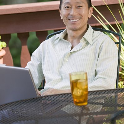 Man sitting outdoors with drink and laptop