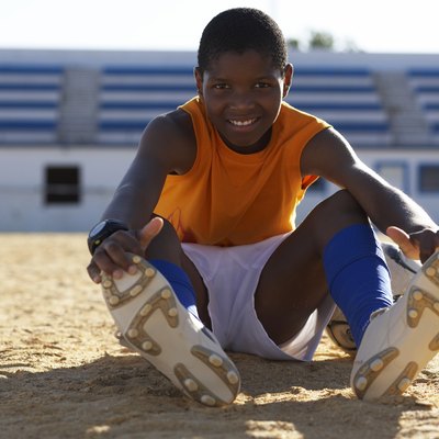 Portrait of boy (10-11) sitting on playing field, stretching