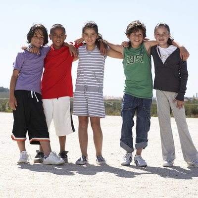 Group portrait of children (9-12) embracing outdoors