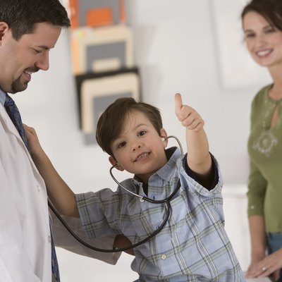 Boy giving thumbs-up while using stethoscope on doctor