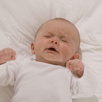 Unhappy baby lying down with eyes closed