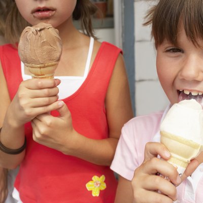 Three girls (6-9) with ice creams, one licking ice cream, portrait