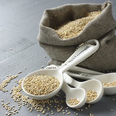 Quinoa grain in small burlap sack and porcelain measuring spoons