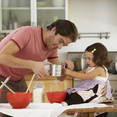 Father and daughter (2-4) baking in kitchen, side view