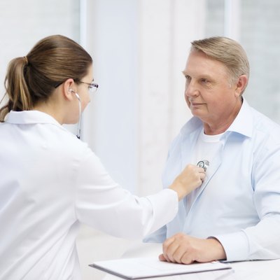 female doctor with old man listening to heart beat