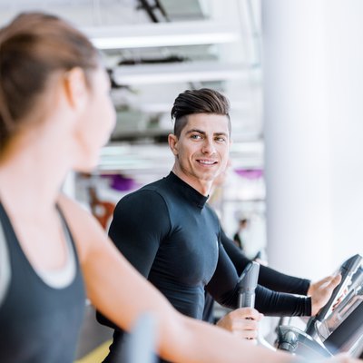 Handsome man and woman using a stepper in a gym