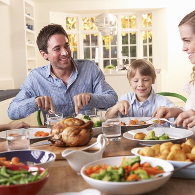 Happy family having roast chicken dinner at table