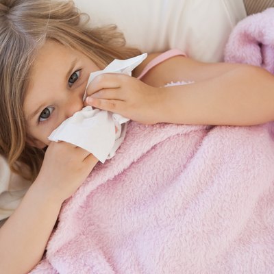 Girl suffering from cold as she lies in bed