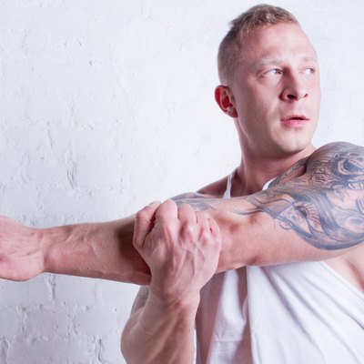 Young man with tattoos stretching arm