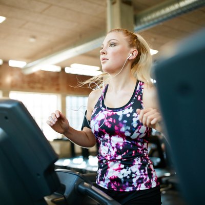 Young female running on treadmill in health club