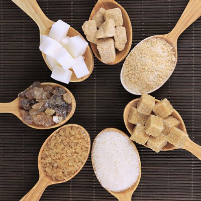 Different types of sugar in spoons on table close-up