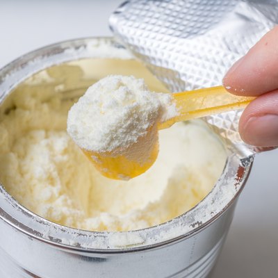 Hand holds scoop with newborn milk formula.