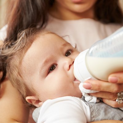 Mother Feeding Baby Boy From Bottle At Home