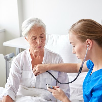 nurse with stethoscope and senior woman at clinic