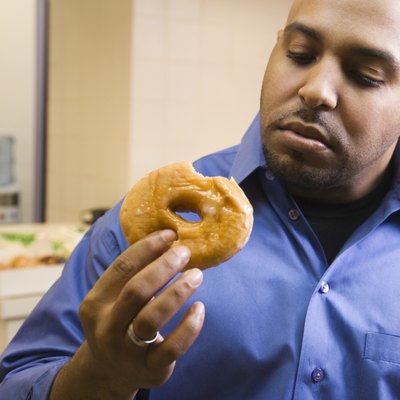 Mixed race businessman eating donut in office