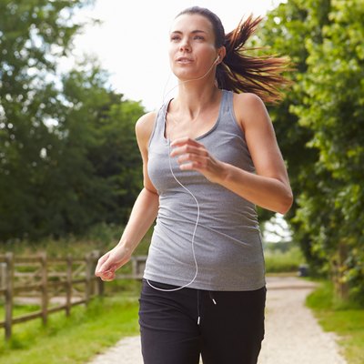 Woman Running In Countryside Wearing Earphones